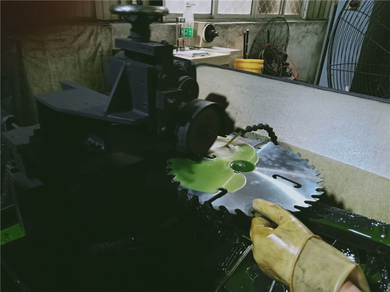 合金鋸片生產(chǎn)車間一角，師傅在給合金鋸片打磨潤(rùn)滑防銹液